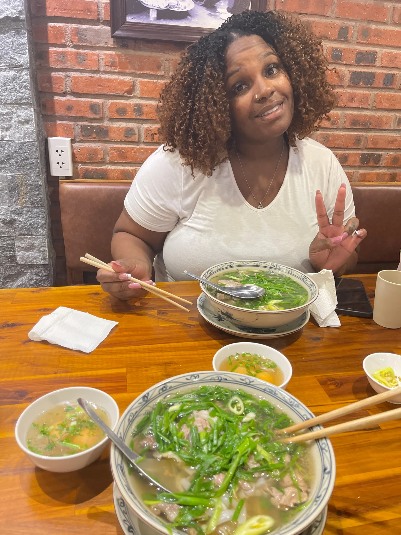 Amia smiling at a café with a bowl of pho